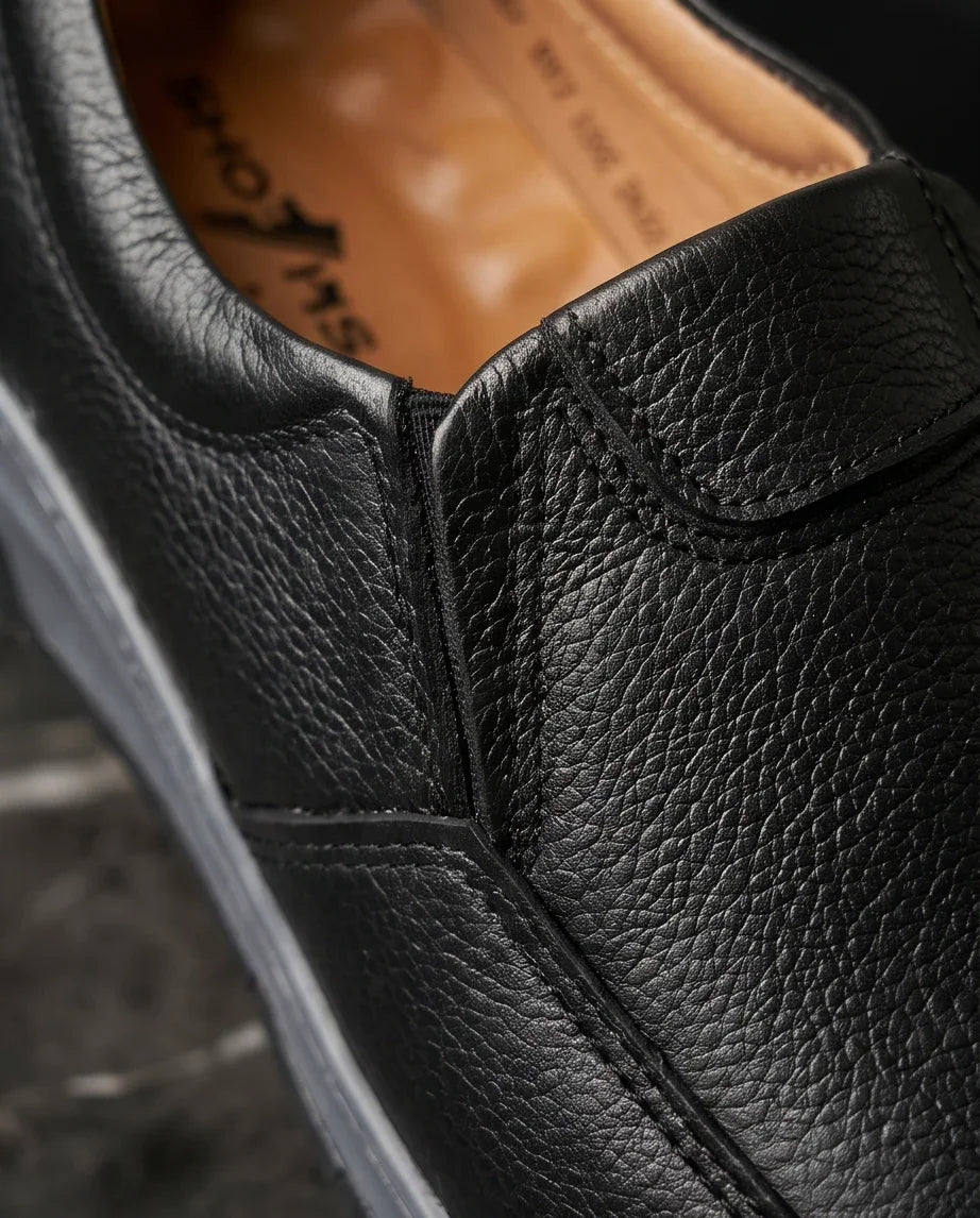 Premium black leather slip-on sneaker with textured finish and white sole, stylish & comfortable footwear