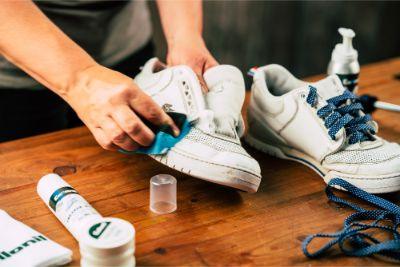Cleaning white sneakers with care products on wooden table